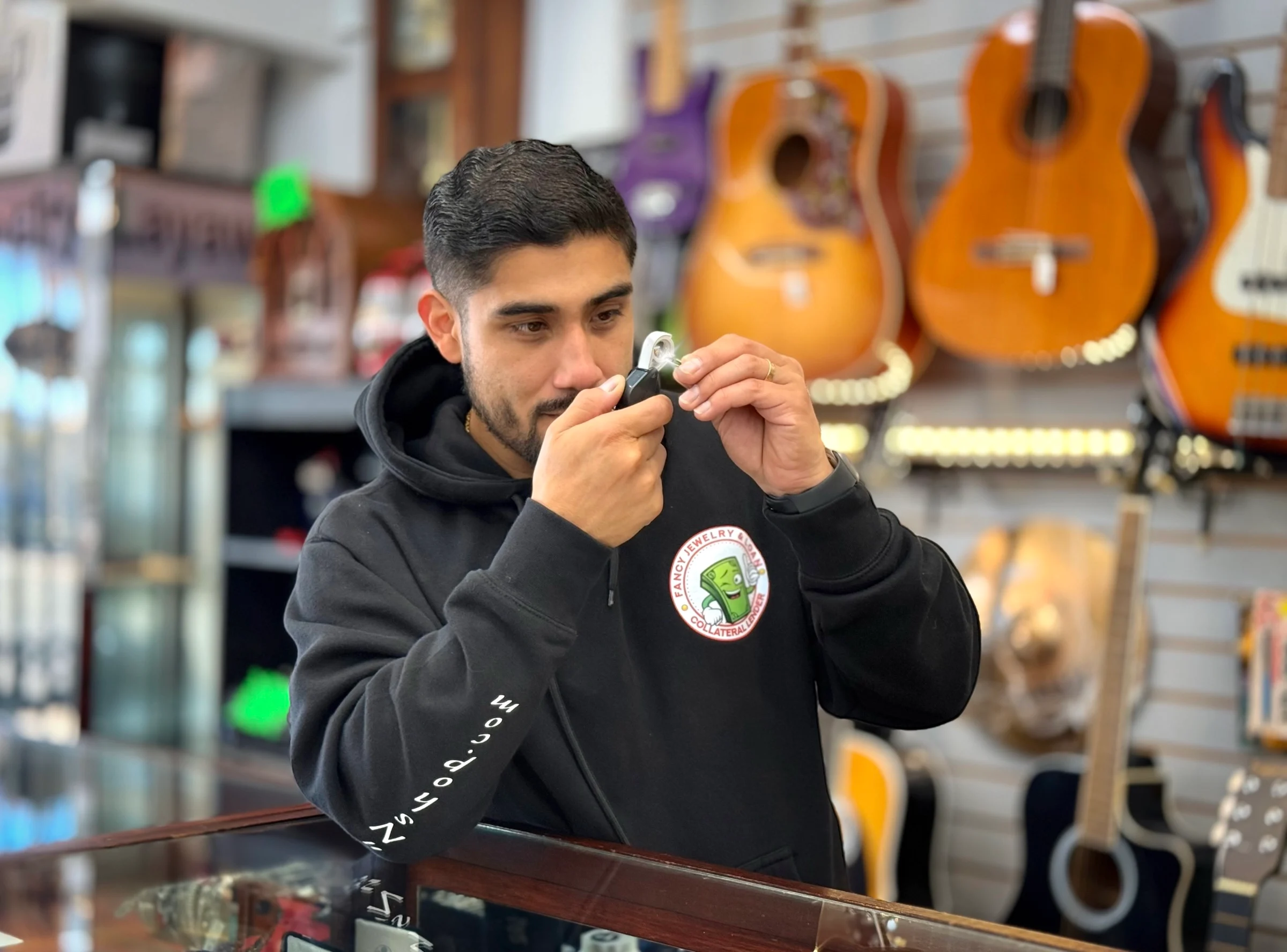 Rene, one of the store managers, carefully inspecting a diamond ring with a loupe.